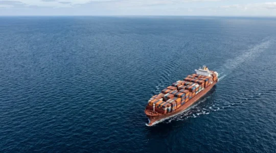 Vue aérienne d'un grand porte-conteneurs chargé de conteneurs multicolores naviguant en pleine mer